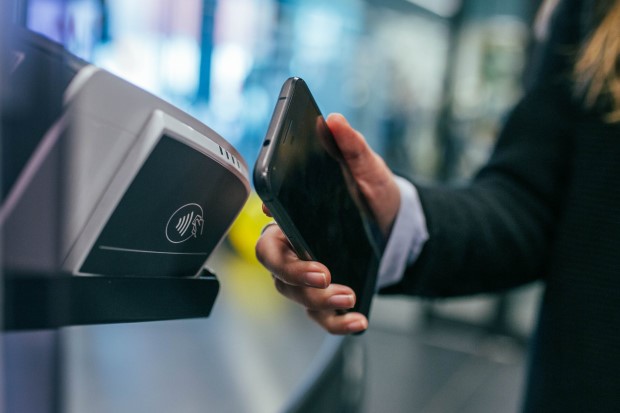 Illustration photo of a person paying with a smartphone using NFC terminal
